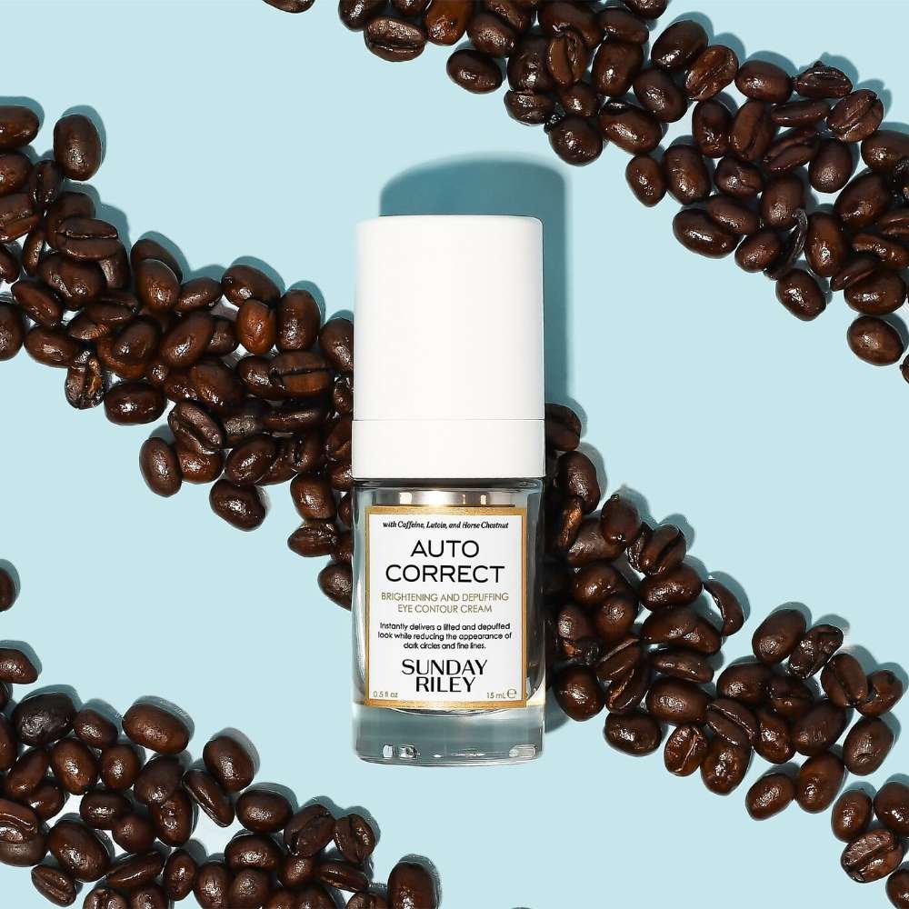 Bottle of Sunday Riley Auto Correct product surrounded by coffee beans on a light blue background